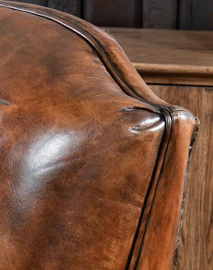 Close-up showcasing the natural variations and texture of the saddle leather upholstery.