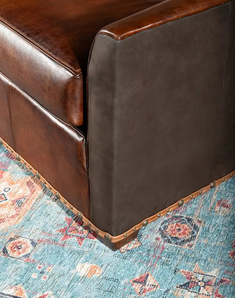 Close-up image focusing on the brass nail tacks along the armrest and base, highlighting the sofa's refined detailing.