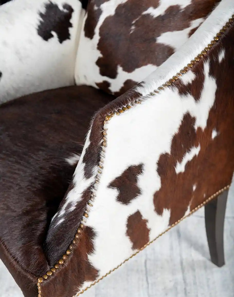 Close-up of the Ebony Cowhide Chair's armrests, highlighting smooth curves, plush padding, and cowhide finishing.