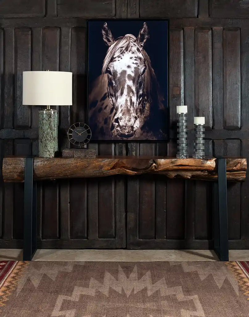 The Black and White Horse Framed Print displayed in a rustic living room setting, paired with a leather armchair and natural wood decor.