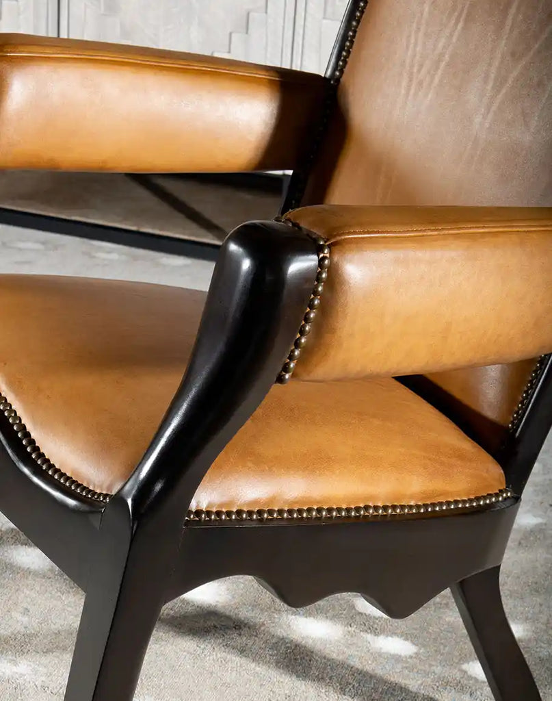 A side-angle view of the Boleyn Leather Chair highlighting its sleek profile, angled backrest, and sturdy hardwood frame.