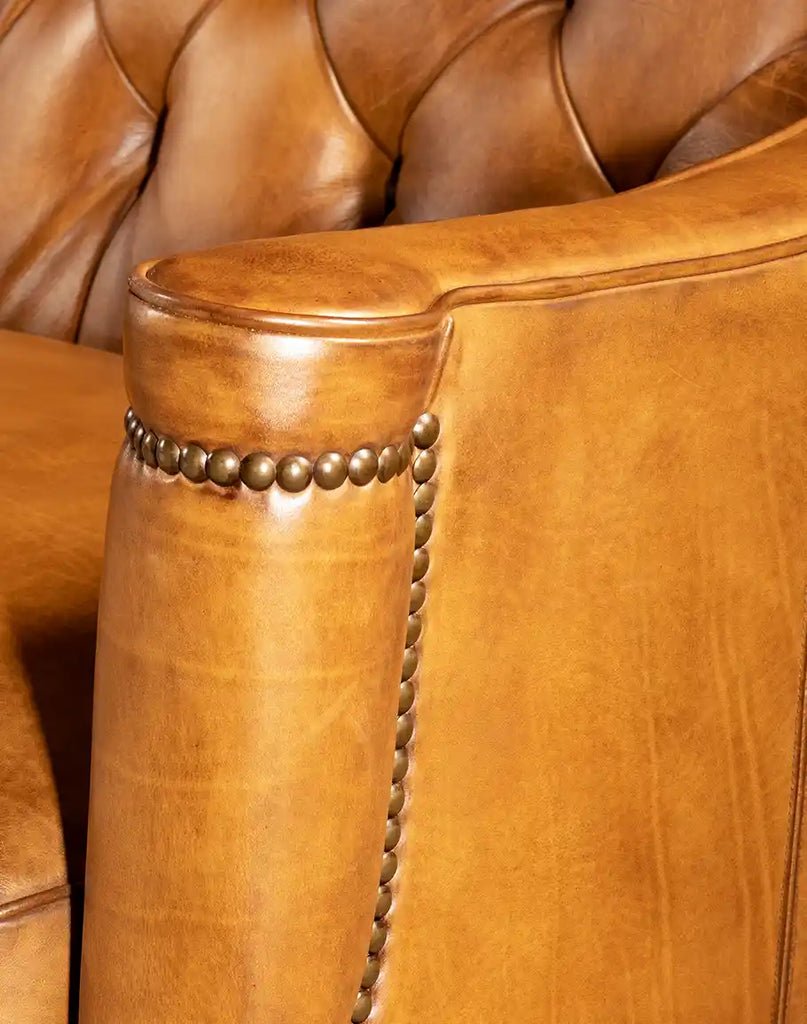 Close-up view of the Brandon Tufted Leather Sofa armrest, showcasing the premium leather finish and decorative brass nailhead trim.