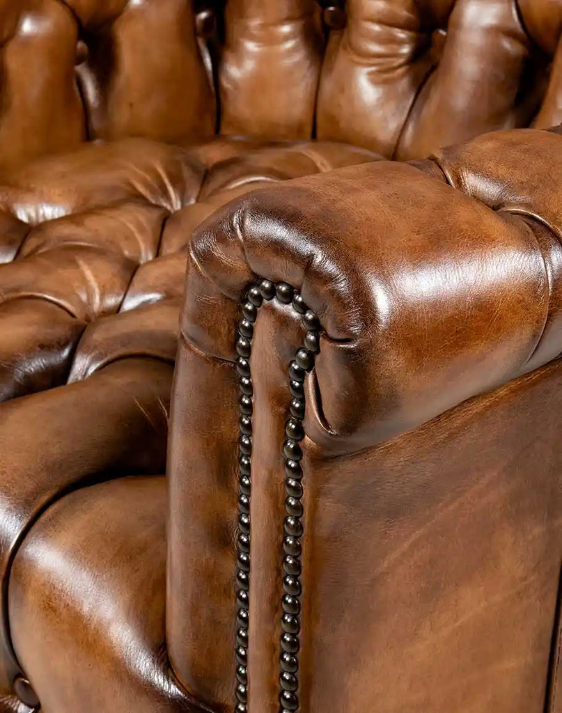 The brass nail head trim along the edges of the Victorian leather chair.