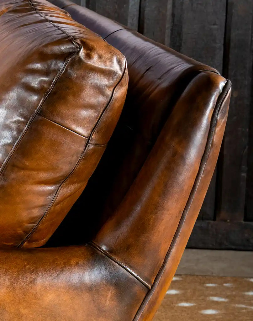 A close-up shot of the hand-burnished leather, emphasizing the rich texture and superior craftsmanship of the sofa.