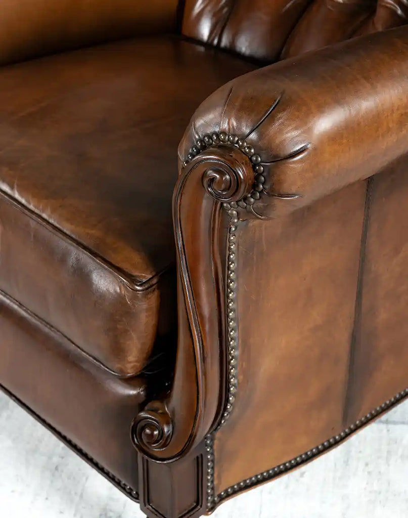 A detailed close-up of the Cameron Leather Recliner's armrest, featuring hand-burnished leather and elegant studding.