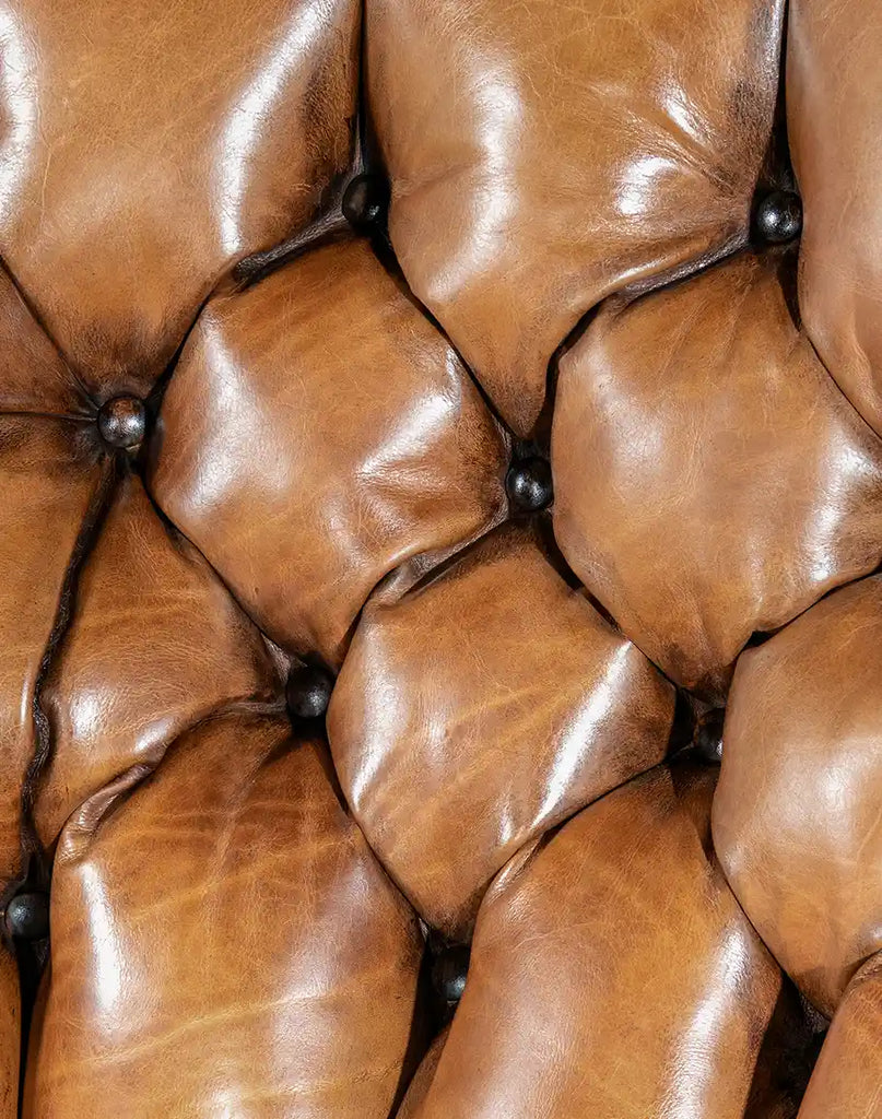 A close-up of the meticulously hand-burnished full-grain leather upholstery of the King Arthur Tufted Chair.