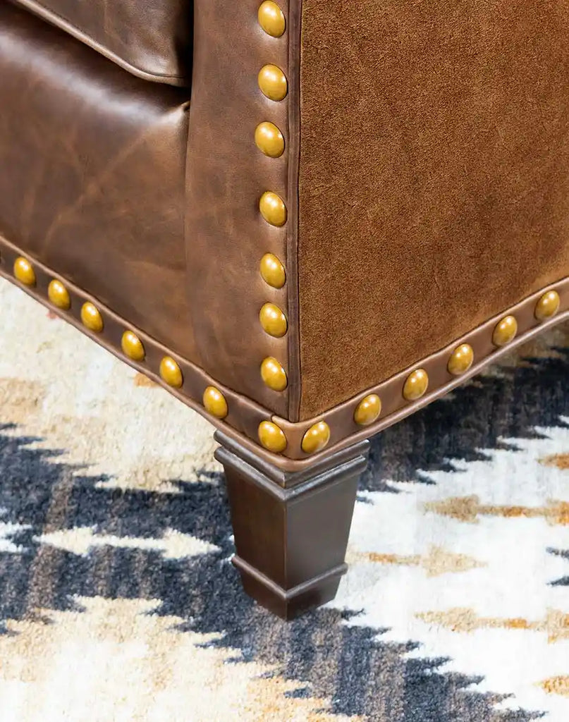 Close-up of the cowboy boot-inspired stitched emblem on the seat back of the Cassie Brown Leather Chair.