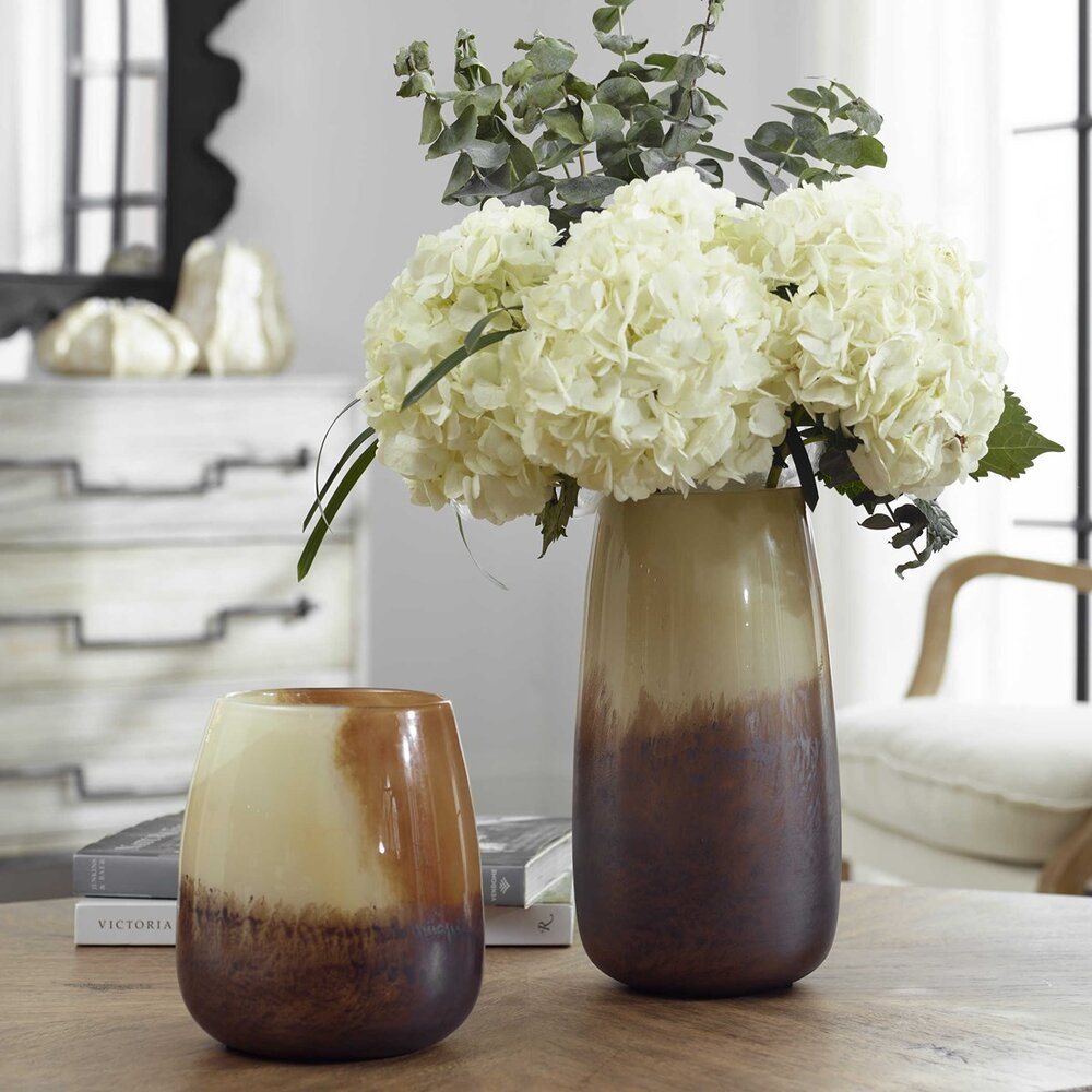 A pair of handcrafted glass vases featuring a unique blend of natural hues, from pale sand to rich rust, perfect for floral or candle displays.