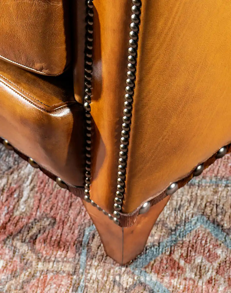 Close-up of the dark wooden legs on the Norseman Leather Chair, providing stability and a touch of rustic charm.