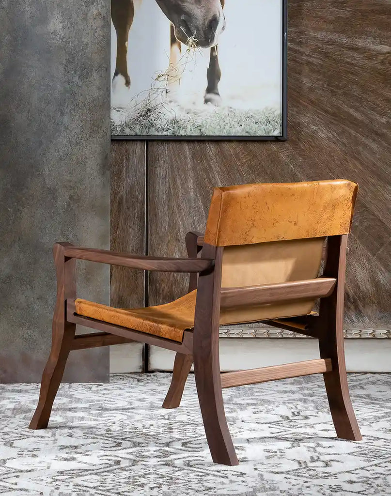 Rear view of the Diego Sling Chair, displaying the curved wooden frame and natural leather variations.