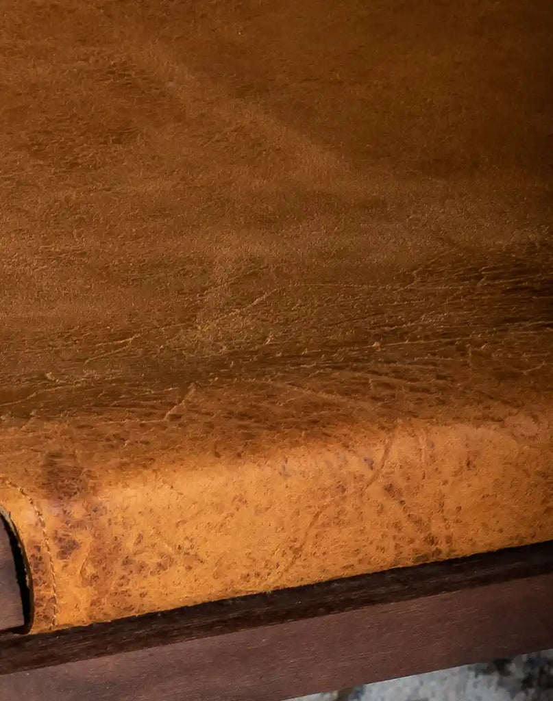 A detailed close-up of the thick, distressed leather seat on the Diego Sling Chair, emphasizing its vintage appeal.