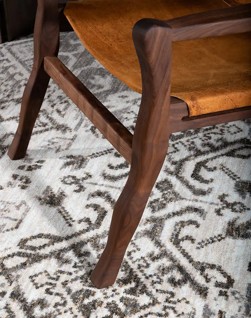 High-quality close-up shot of the oil-finished black walnut wood frame, showing the craftsmanship of the Diego Sling Chair.