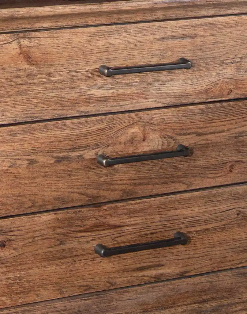 A close-up view of the El Paso Triple Drawer Nightstand’s drawer fronts, highlighting the rustic Pecky Hickory Veneers and elegant dark brushed bronze bar pulls.