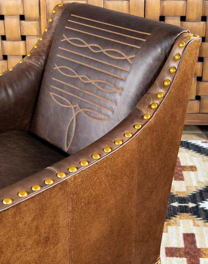 Side angle showing the Cassie Brown Leather Chair's gracefully curved arm design with brass nailhead detailing.