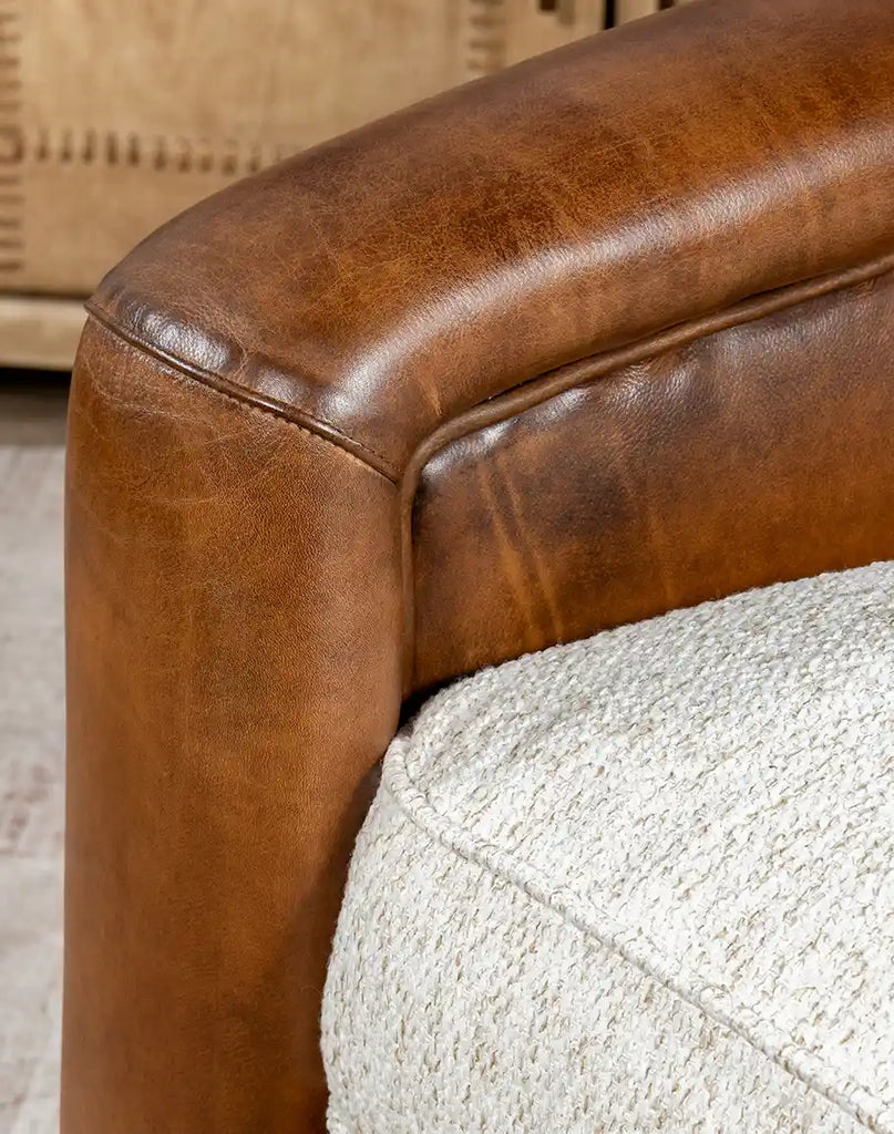 Close-up of the Elsa Bark Swivel Chair's armrest, featuring leather upholstery and precise stitching.