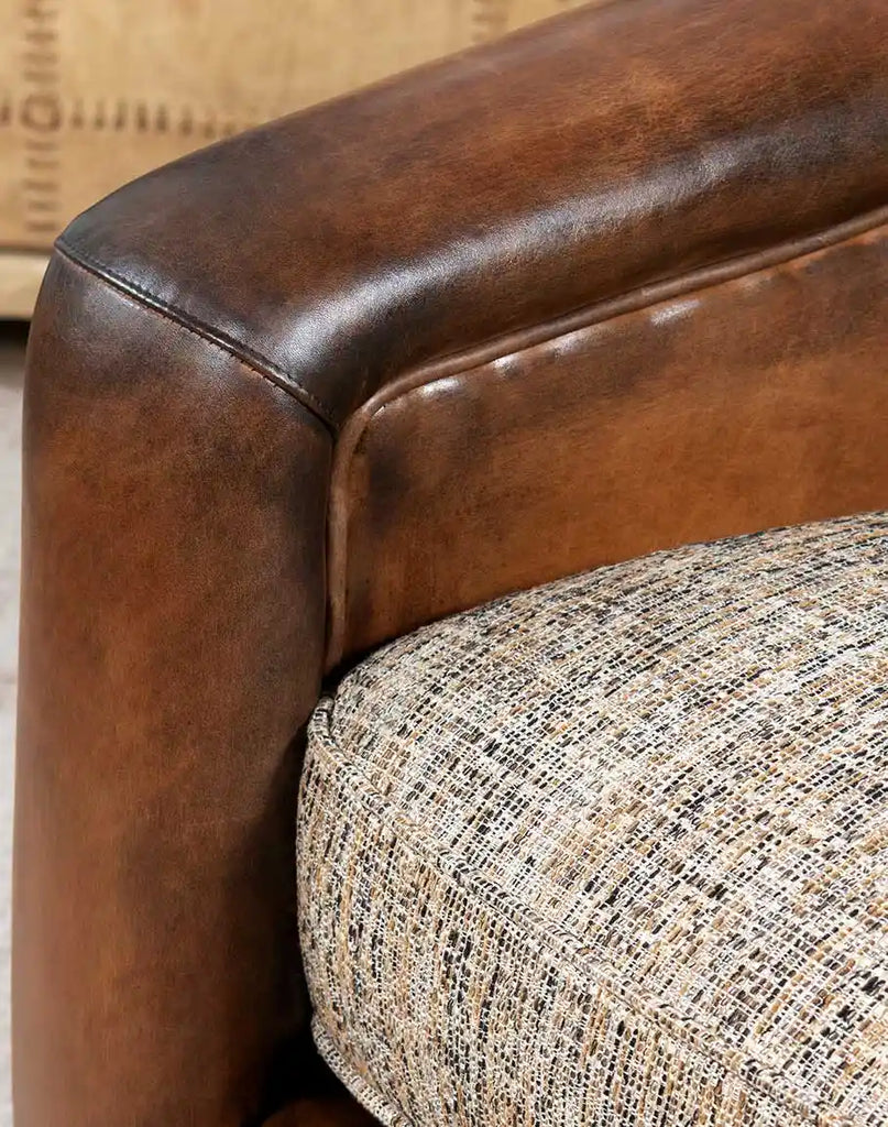 Close-up of the Elsa Cocoa Swivel Chair's armrest, highlighting the hand-burnished leather and precise stitching.