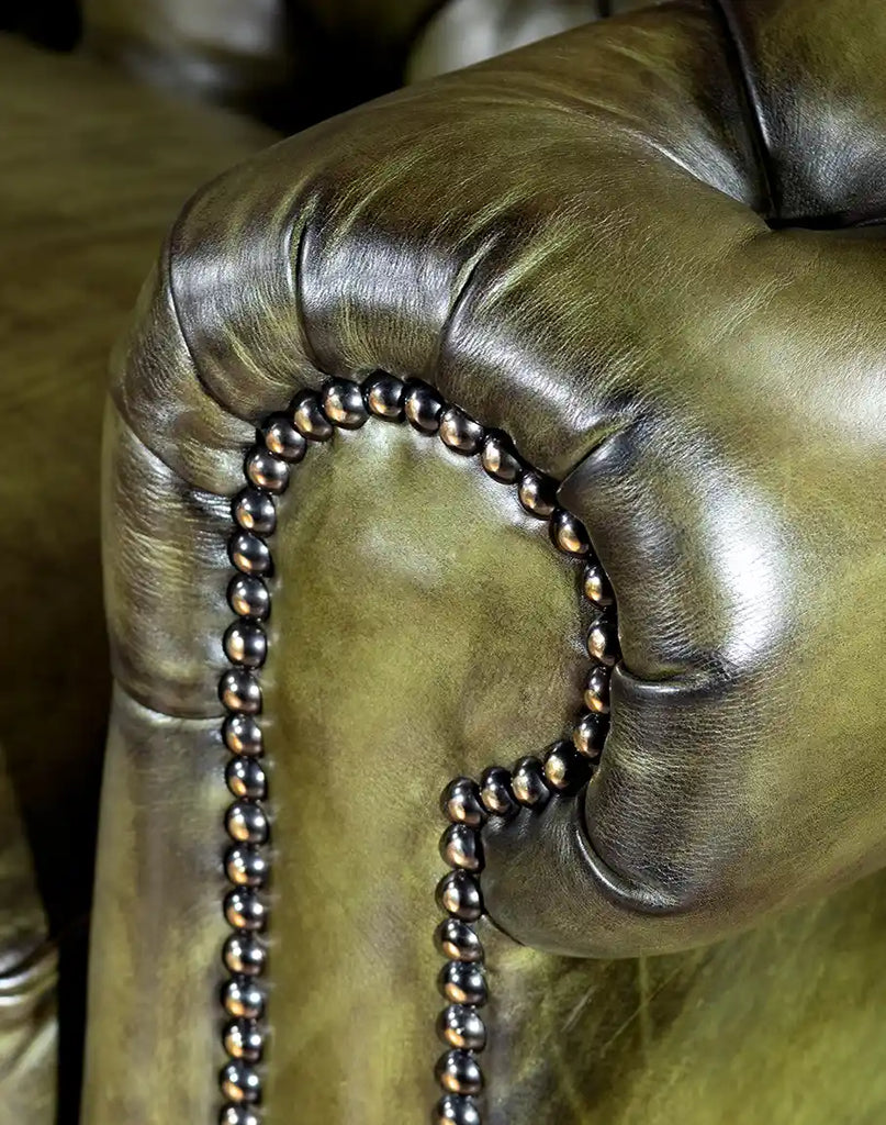 Close-up view of the brass nail tacks elegantly outlining the bottom border of the sofa.