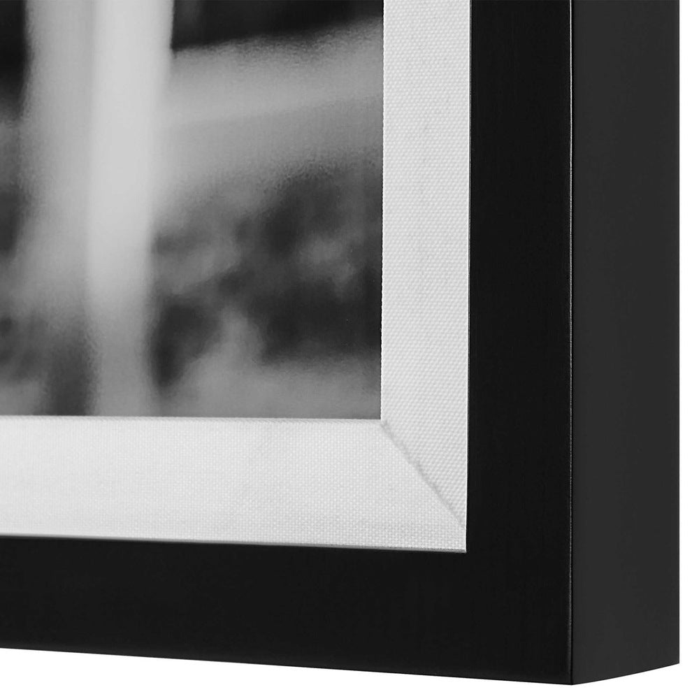 Framed black-and-white art print set against a natural background.