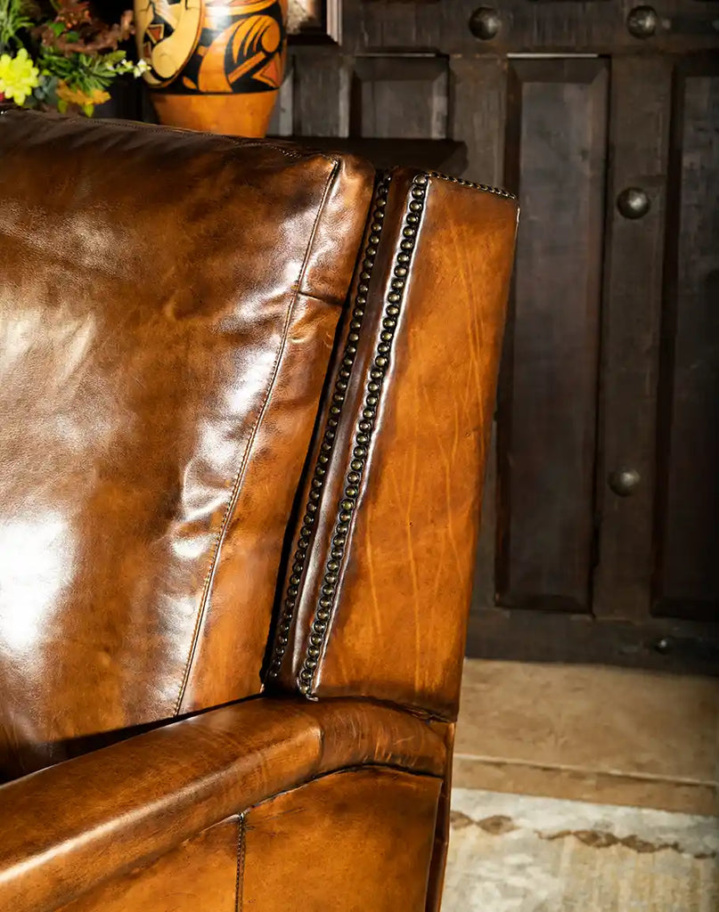 A detailed close-up of the recliner's supple hand-burnished leather, showcasing its luxurious texture and craftsmanship.