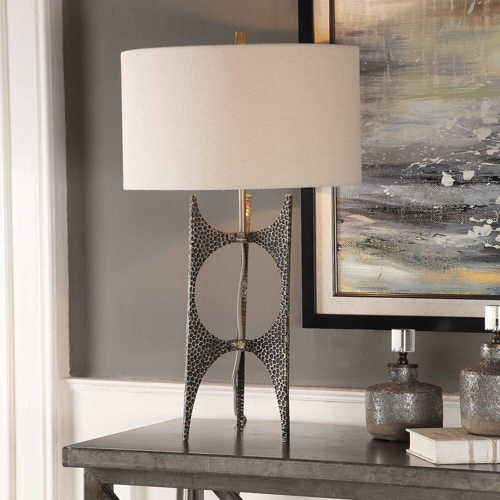 Cast iron table lamp featuring a hammered texture, golden bronze finish, and a white linen drum shade for a sophisticated touch.