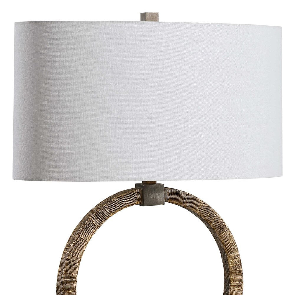 Artistic table lamp showcasing tribal hand-carved gold details, dark bronze highlights, and a clean white linen oval shade for elegance.