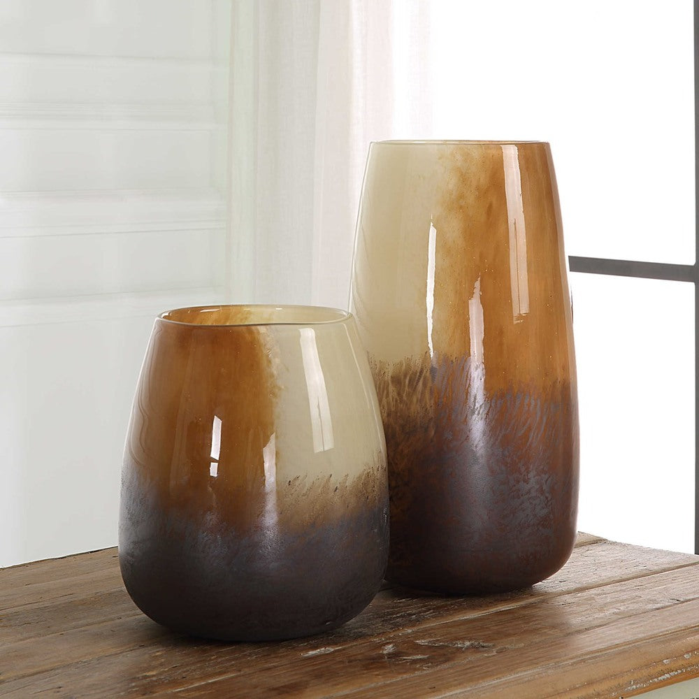 A collection of glass vases featuring warm, neutral colors like sand, rust, and bronze, ideal for styling with florals or candles.