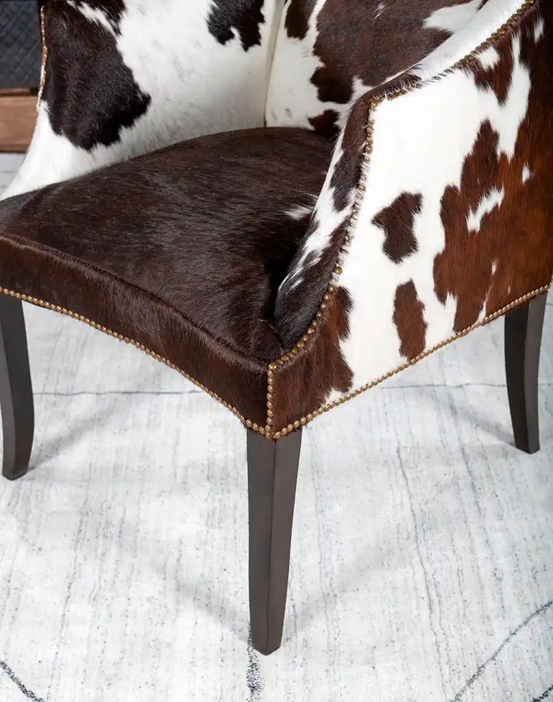 A focused view of the solid hardwood legs of the Ebony Cowhide Chair, showcasing their durability and rustic finish.