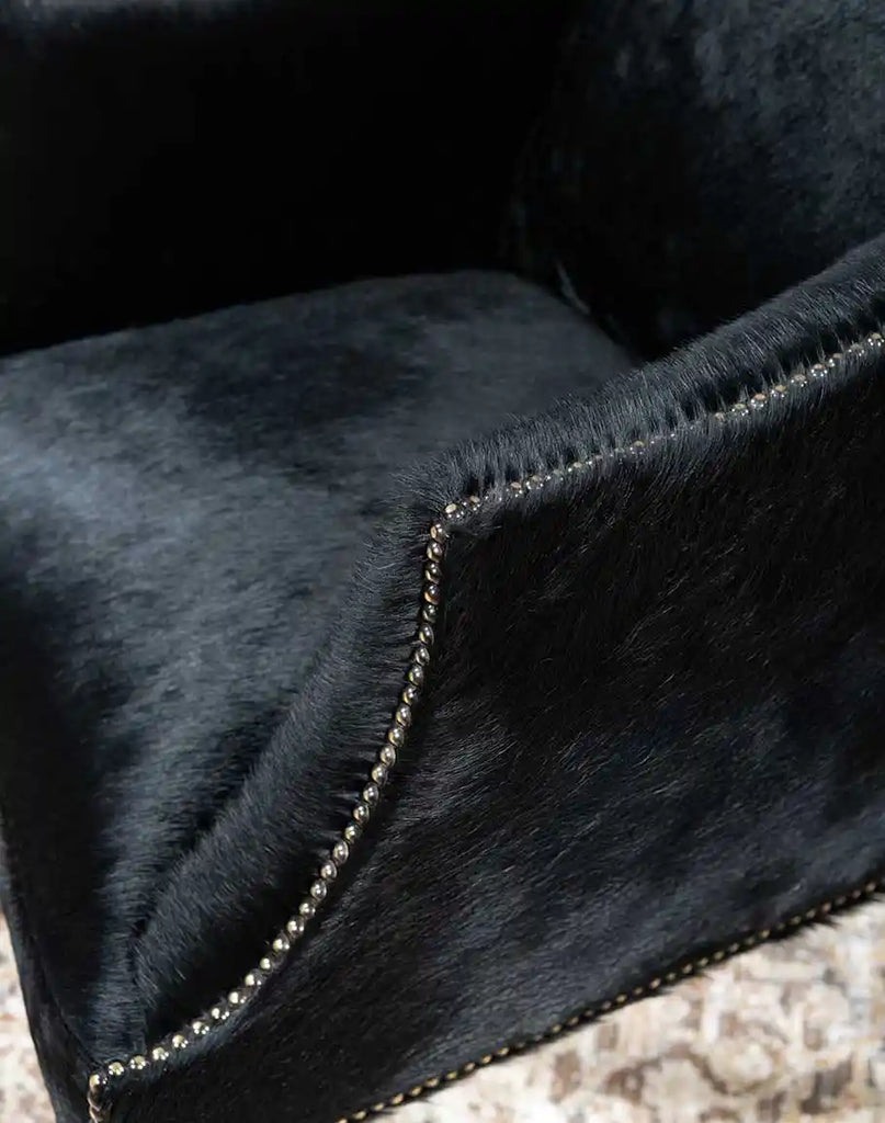 A close-up view of the hand-stitched seams and antique nailhead trim on the McClaren Midnight Cowhide Chair, emphasizing expert craftsmanship.