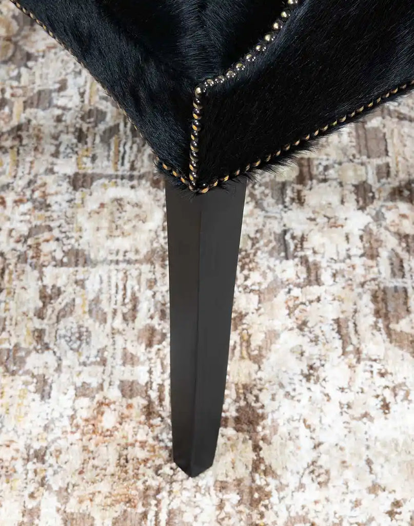 A close-up of the strong wooden legs on the McClaren Midnight Cowhide Chair, providing durability and a refined rustic touch.