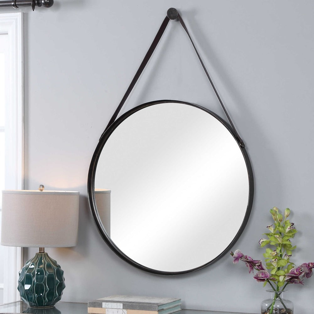 Modern bronze round mirror with adjustable faux leather straps and a decorative hanging hook.
