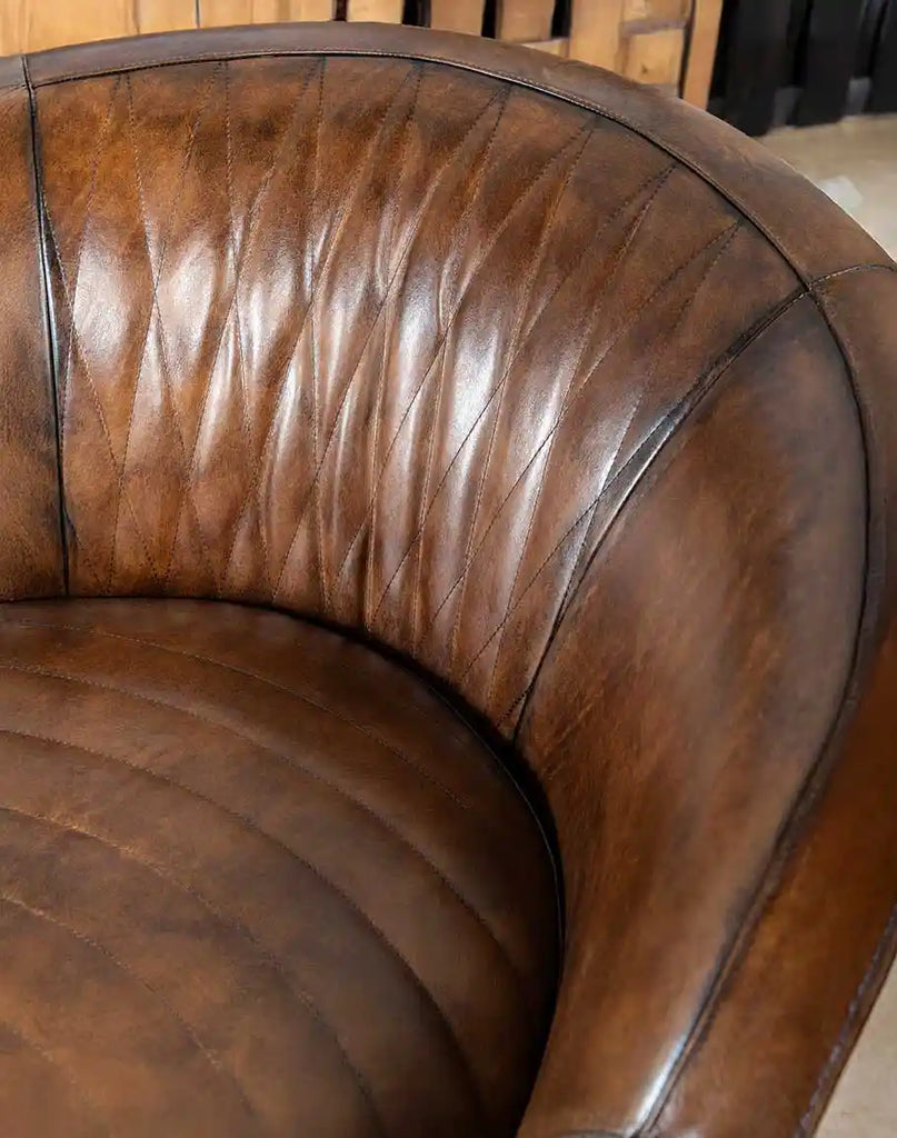 A detailed close-up of the full-grain mocha leather on the Moscow Mocha Swivel Chair, emphasizing its natural grain and hand-finished patina.