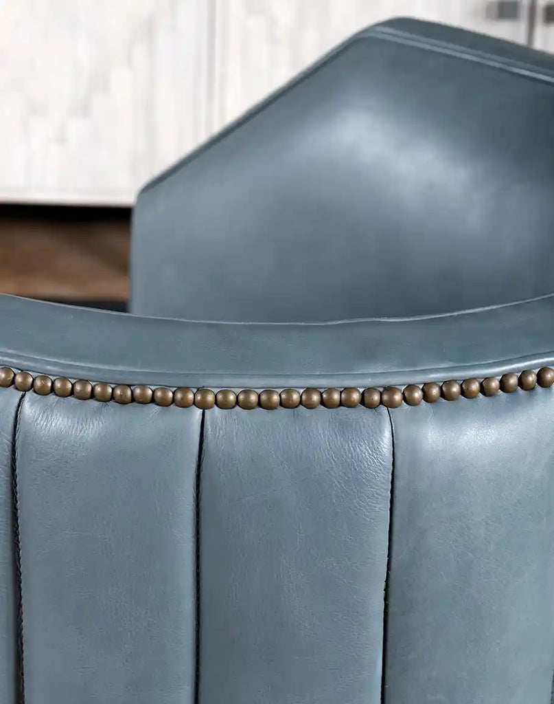 Close-up of the brass nail tack trim, offering a refined contrast against the slate blue leather.