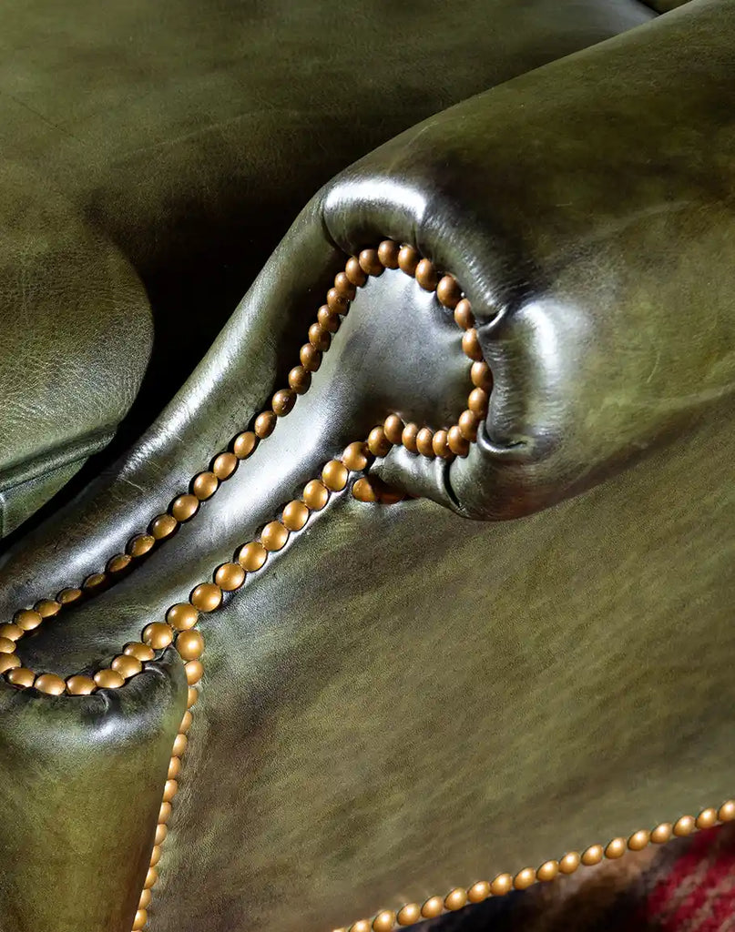 Close-up of gold nail tacks on the Olive Green Wingback Chair, adding a touch of opulence to the design.