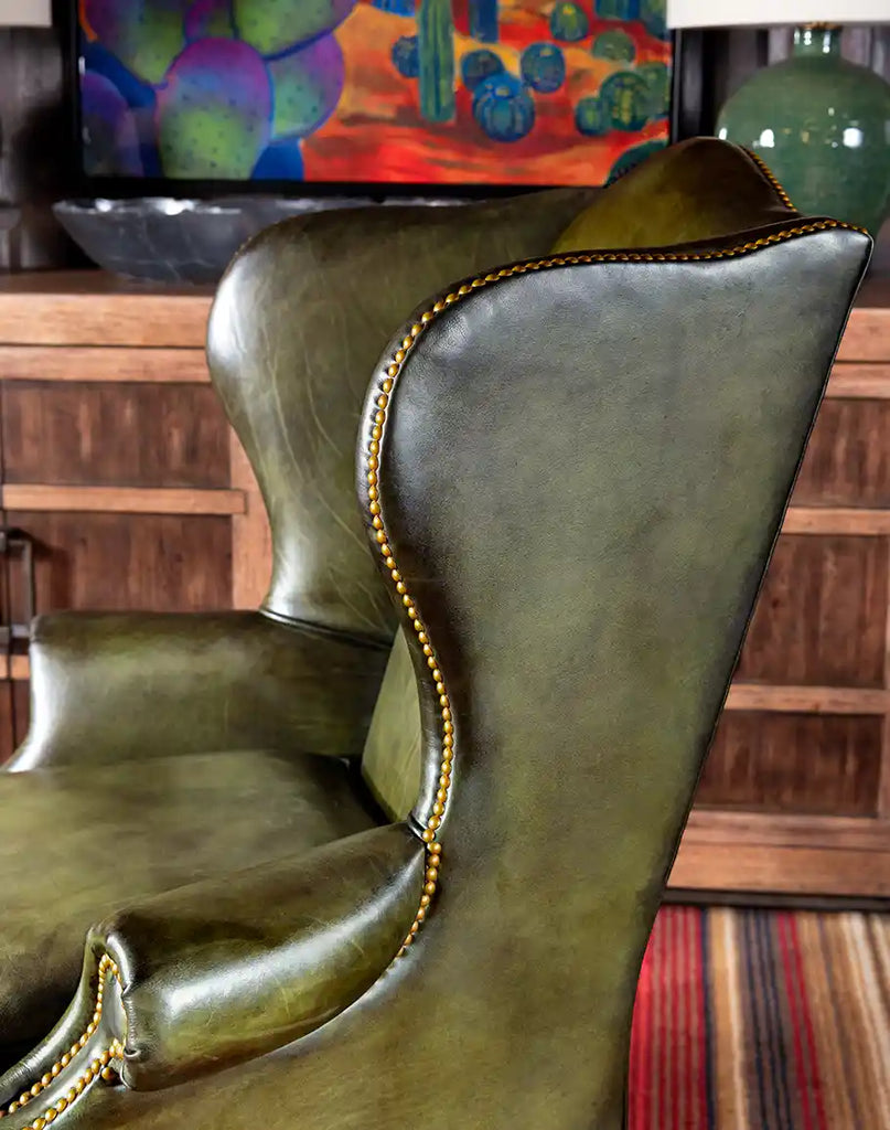 Gold nail tacks accentuating the Olive Green Wingback Chair's elegant design details.