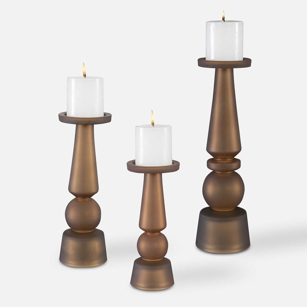 Pantheon Candleholders set in matte butter rum glass, featuring three traditional silhouettes with white candles.