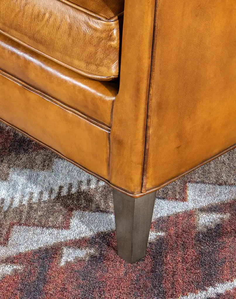 A close-up of the Reno Club Chair’s strong wooden legs, featuring a rich finish that complements the luxurious leather.