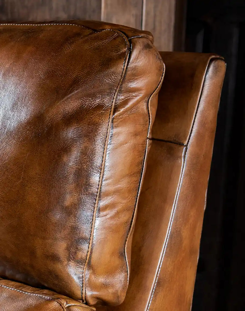 Close-up of the full-grain leather upholstery on the Revolt Bourbon Recliner, showcasing its texture and quality.