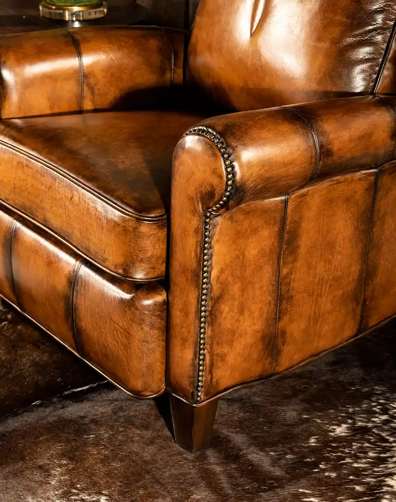 A detailed close-up of the Richard King Recliner armrest showcasing rich, hand-burnished leather and intricate studded accents, highlighting craftsmanship and luxurious design.