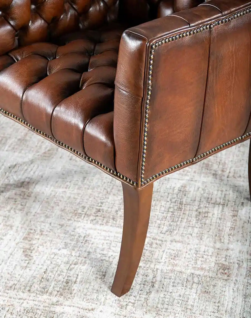 Detailed view of the Roan Sable Tufted Leather Chair's gracefully curved legs, adding a touch of elegance to its design.