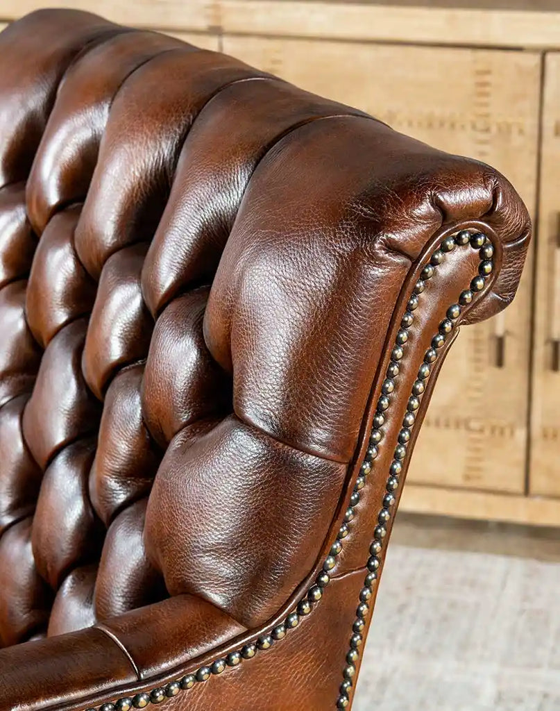 Detailed image of the brass nail tacks accentuating the outside wing panels and arms of the Roan Sable Tufted Leather Chair.