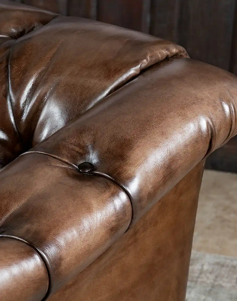 Close-up of the hand-brushed full-grain leather texture on the Rockwood Smoked Chesterfield Sofa, in smoky bronze and chocolate tones.