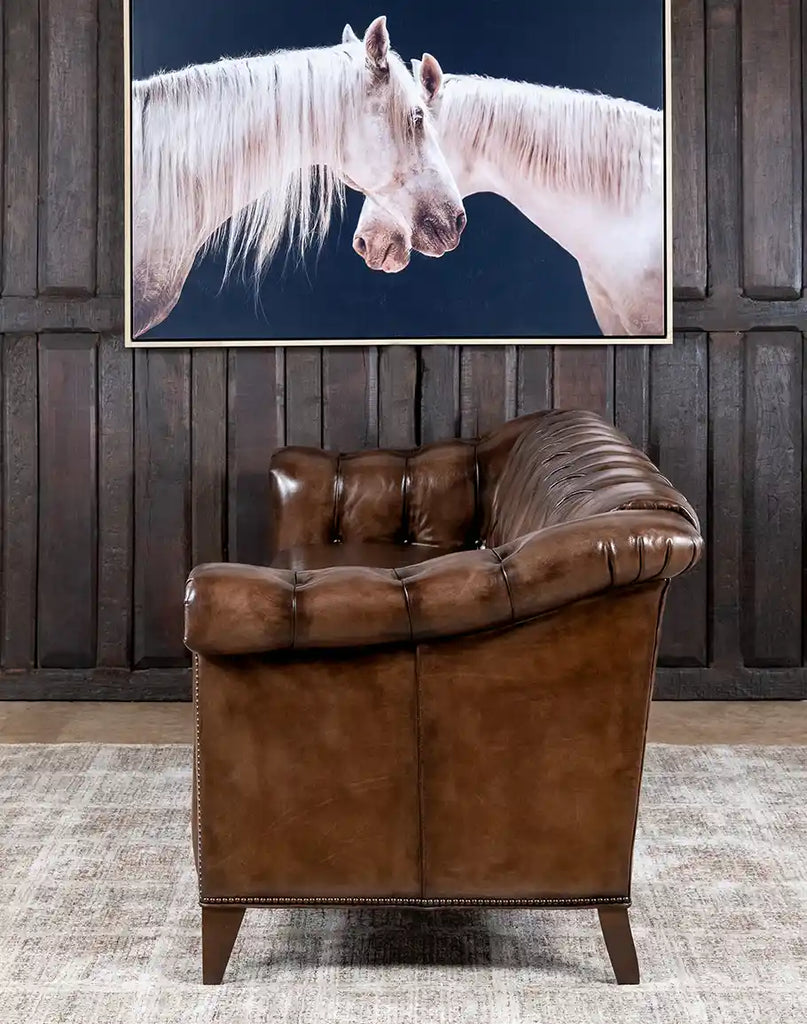 Side profile of the Rockwood Smoked Chesterfield Sofa, featuring sleek lines, hand-brushed leather accents, and brass nail tacks.