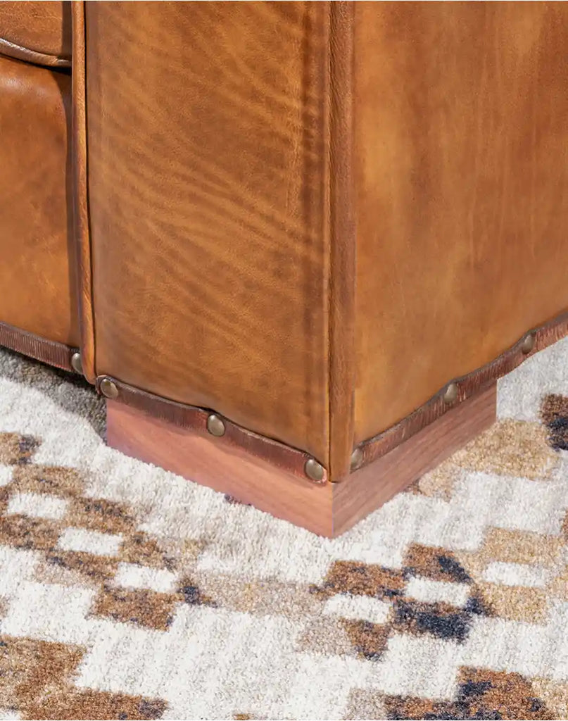 Detailed shot of the Ruby Cognac Leather Sofa's solid black walnut feet with a natural oiled finish.