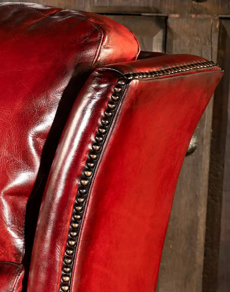 A close-up shot of the elegant bronze nail head trim accentuating the classic design of the Ruby Red Leather Recliner.