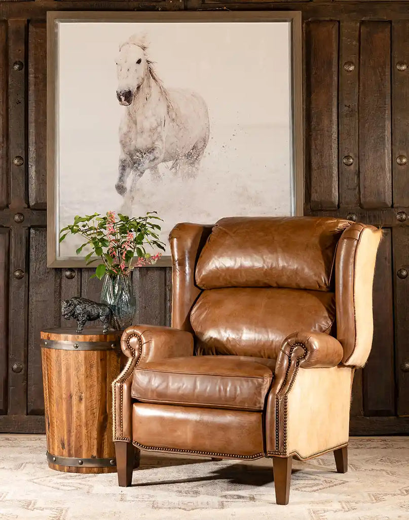 The Run Wild Framed Print featuring a galloping white horse displayed in a rustic room with a leather armchair, wooden side table, and decorative accents.