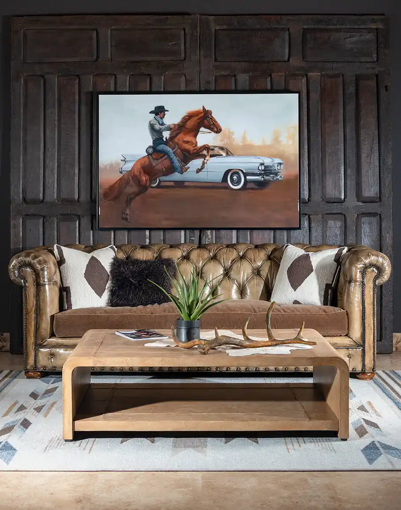 The Sahara Sand Leather Coffee Table styled in a rustic living room, complementing the space with its warm palomino leather and modern design.