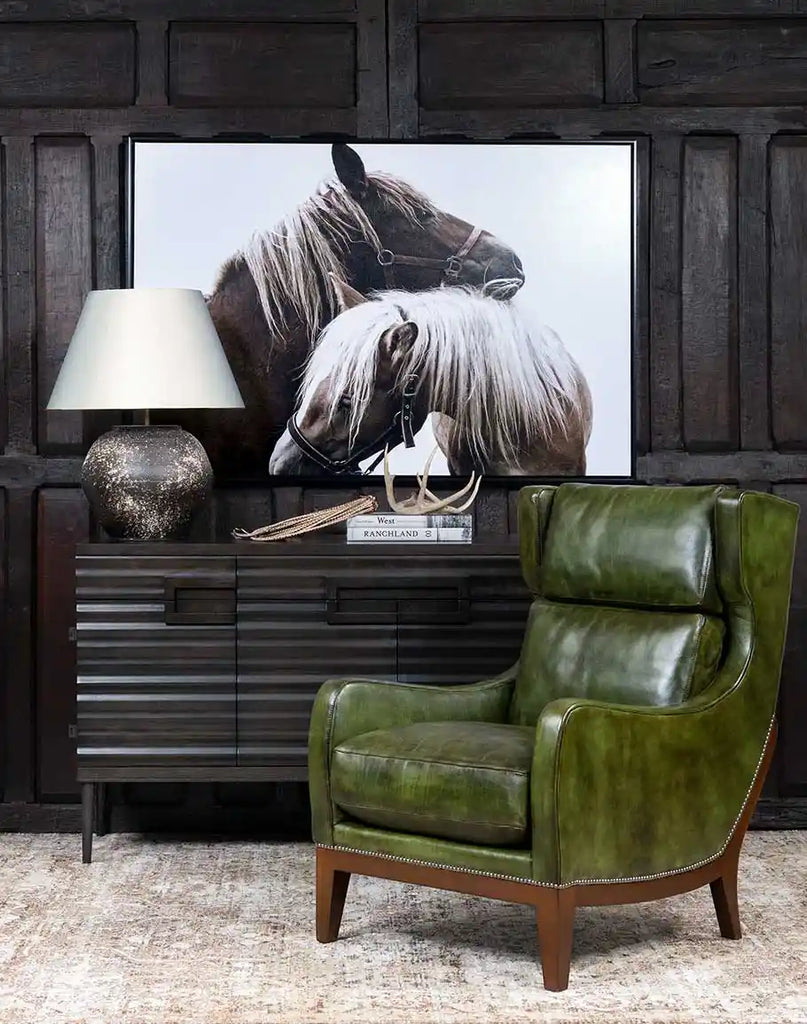 The Seabrook Moss Leather Chair styled in a cozy living room, paired with a rustic side table and warm lighting.