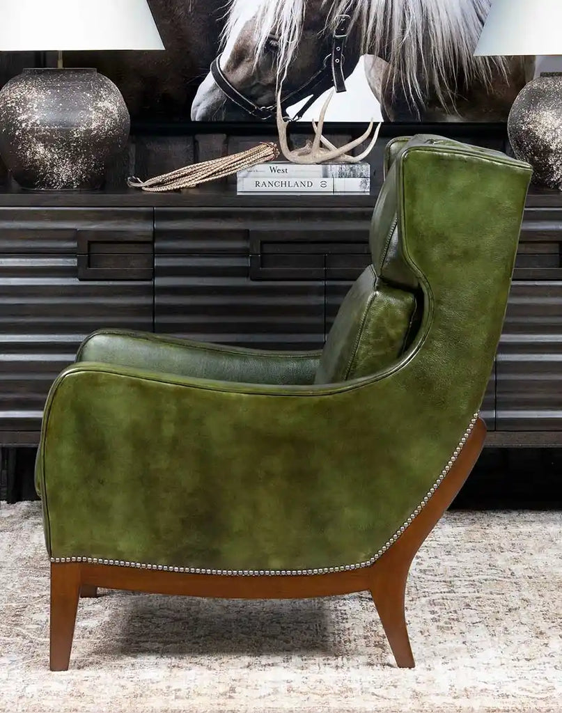 A side-angle view of the Seabrook Moss Leather Chair, highlighting its curved arms, plush cushioning, and expert craftsmanship.