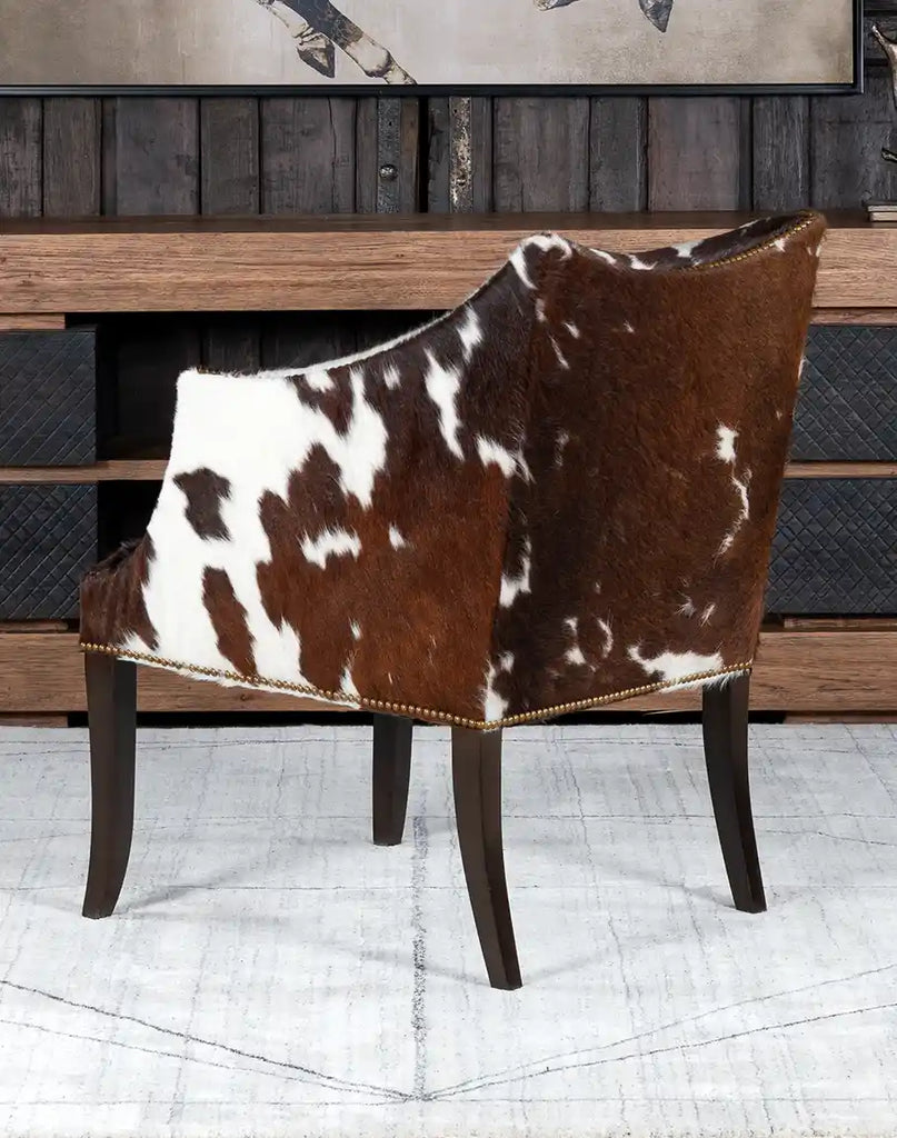 Side angle view of the Ebony Cowhide Chair displaying the curved armrests, smooth cowhide details, and sturdy hardwood legs.