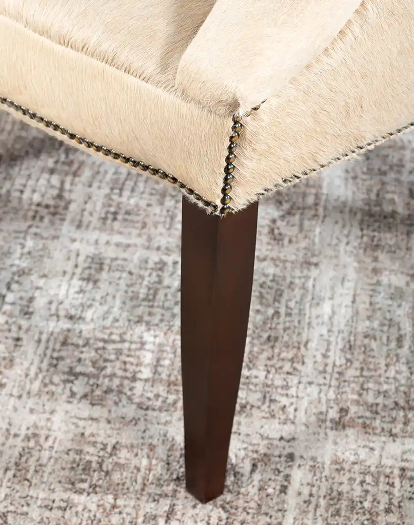 A detailed view of the solid hardwood legs of the Hertfordshire Sand Cowhide Chair, emphasizing its durability and polished finish.